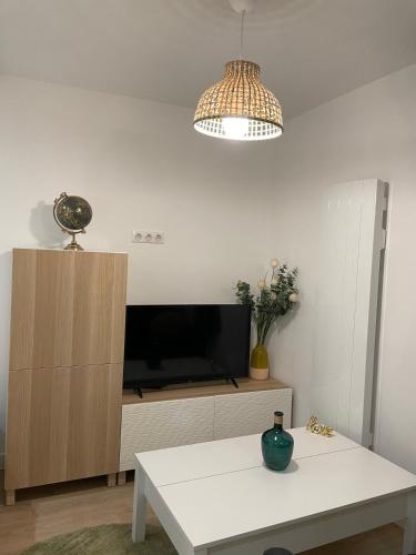 a living room with a tv and a white table at Superbe Studio Meublé - Houdan in Houdan