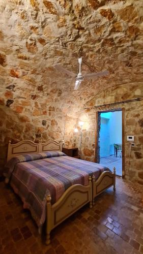 1 dormitorio con 1 cama en una pared de piedra en B&B Nuraximannu, en Santadi