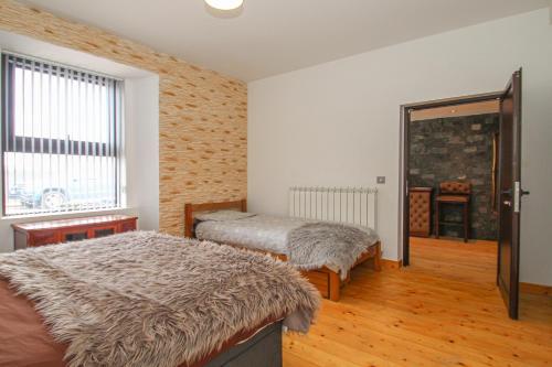 sypialnia z 2 łóżkami, oknem i drzwiami w obiekcie Deluxe Apartment w mieście Lanark