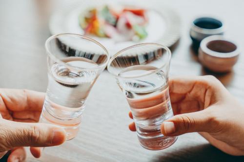 two people holding two glasses of water on a table at NIPPONIA 田原本 マルト醤油 in Nara