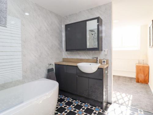 哈德斯菲爾德的住宿－Asquith Penthouse，浴室设有白色浴缸、水槽和镜子