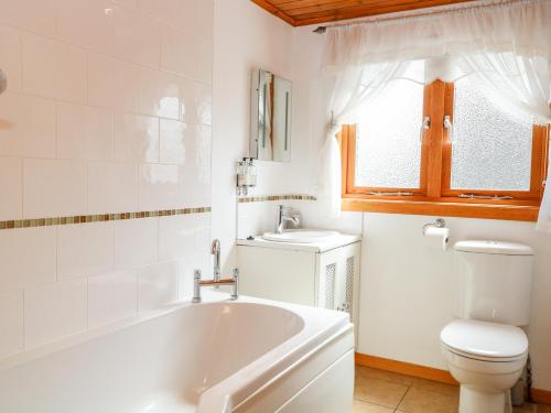 a bathroom with a tub and a toilet and a sink at Harmony House in Great Yarmouth