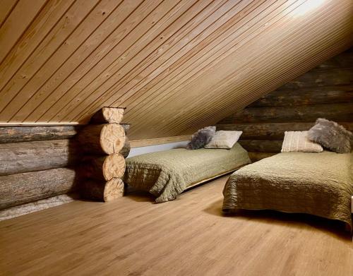 a attic bedroom with two beds and a log wall at Levi Ski IN Ski OUT Premium VillaWestWind B in Levi