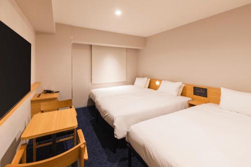 a hotel room with two beds and a flat screen tv at Sotetsu Fresa Inn Sapporo-Susukino in Sapporo