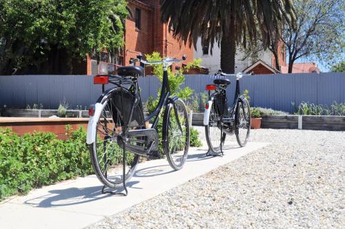 deux vélos garés l'un à côté de l'autre sur un trottoir dans l'établissement CIRCA 1936 Art Hotel, à Corowa