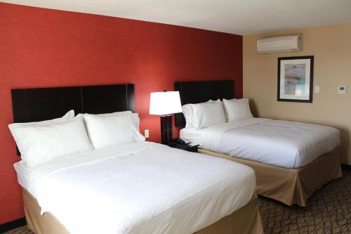 Holiday Inn Salina, an IHG Hotel في سالينا: سريرين في غرفة الفندق بجدران حمراء