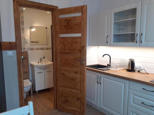 a kitchen with a wooden door and a sink at Apartamenty nad Jeziorem in Międzybrodzie Żywieckie