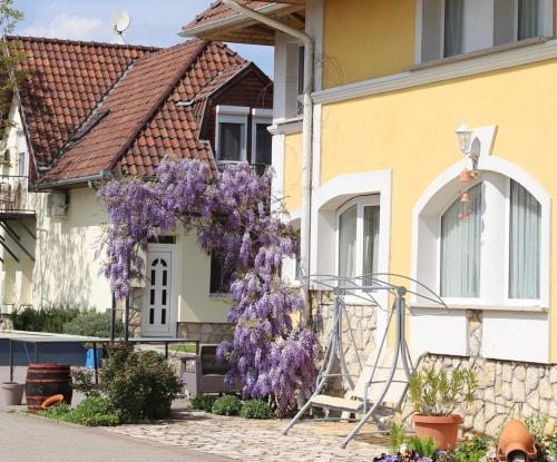 a house with wisteria on the side of it at Jade Panzio in Balatonföldvár