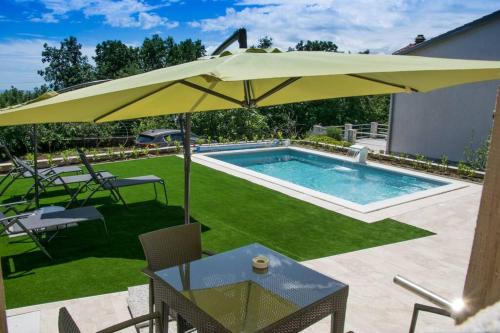 een patio met een parasol en een zwembad bij Luxury Flat with Heated Pool & Jacuzzi in Rijeka