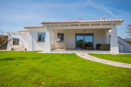 a white house with a patio and green lawn at ENAJA - Luxury Retreat in Budoni