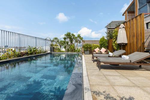 a swimming pool with two chaise lounges next to a building at Moon Hotel and Apartment Da Nang in Danang