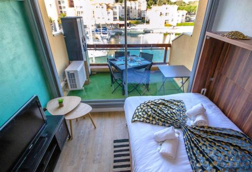 - une chambre avec un lit et un balcon avec vue dans l'établissement MER.Veilleuse YourHostHelper, à Gruissan