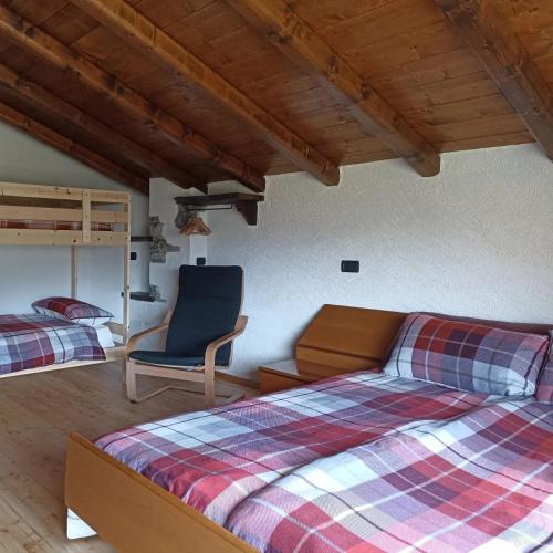 a bedroom with two beds and a blue chair at Baita Eleonora in Argegno