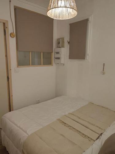 Cette chambre blanche comprend un lit et un lustre. dans l'établissement Mimi&Cosy, appartement en bord de mer à Six-Fours-les-plages, à Six-Fours-les-Plages