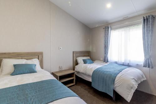 a bedroom with two beds and a window at Stunning 6 Berth Lodge With Partial Sea Views In Suffolk Ref 68007cr in Lowestoft