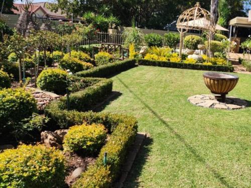 einen Garten mit einer Statue in der Mitte eines Gartens in der Unterkunft Villa Rose Cottages in Bloemfontein