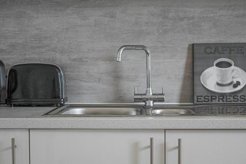 a stainless steel kitchen sink with a coffee mug on a coaster at Station Signature Apartment near Lanark in Carstairs