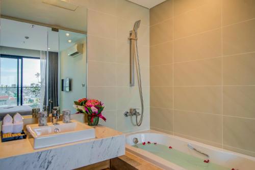 a bathroom with a tub and a sink and a mirror at Moon Hotel and Apartment Da Nang in Danang