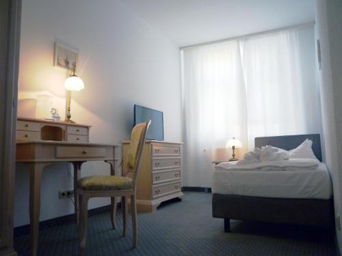 a bedroom with a desk and a bed with a dresser at Hotel Esplanade Garni in Kühlungsborn