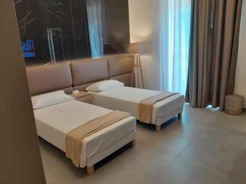 a hotel room with two beds and a window at BAARIA House Hotel in Barcellona-Pozzo di Gotto