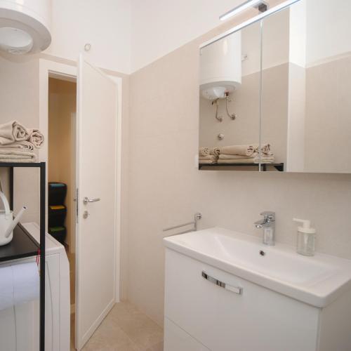 a white bathroom with a sink and a mirror at New! Urban apartment with free parking in Trogir