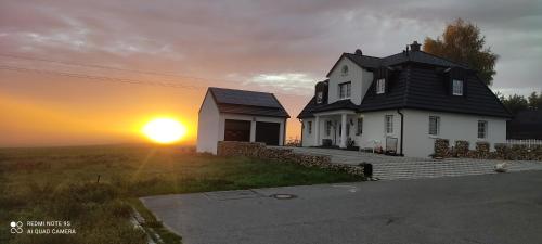 a white house with the sun setting behind it at Ferienwohnung Firmenmietwohnung Jurastein in Deining