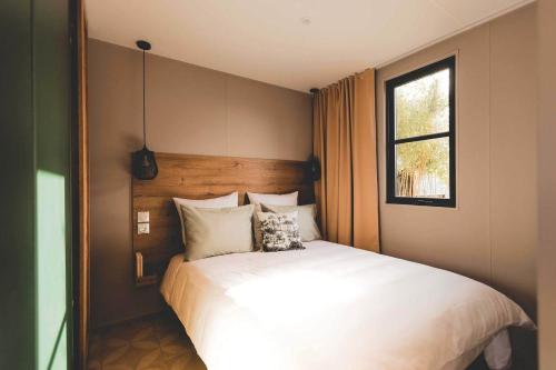 a bedroom with a large white bed with a window at Camping Country Park Crecy La Chapelle - Site Officiel - Next to Disneyland Paris in Crecy la Chapelle