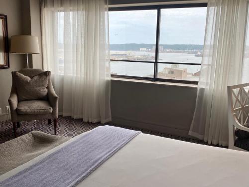 a bedroom with a bed and a chair and a large window at The Royal Hotel by Coastlands Hotels & Resorts in Durban