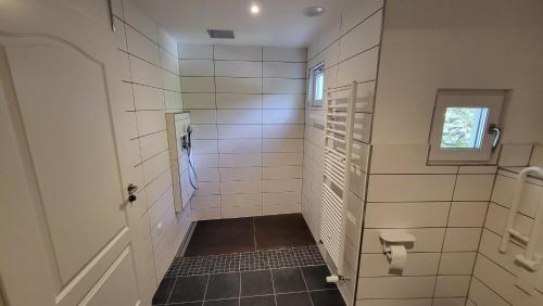 La salle de bains est pourvue de murs carrelés blancs et d'une porte. dans l'établissement Maal Waldhaus, à Todtnau