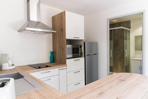 une cuisine avec des armoires blanches et un réfrigérateur en acier inoxydable dans l'établissement Studio Charmant U Pinu, 2 personnes, 6 Kms de Porto Vecchio, à Porto-Vecchio