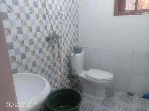 a bathroom with a white toilet and a sink at Warung Rizka in Probolinggo