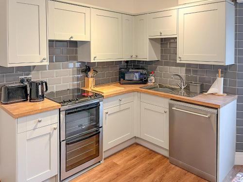 a kitchen with white cabinets and stainless steel appliances at Seaview in Gorran Haven