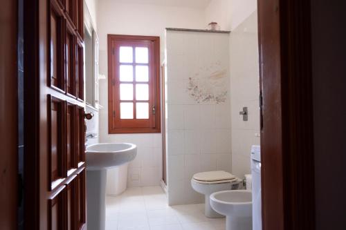 een badkamer met een wastafel, een toilet en een raam bij Casa Enza di fronte la Tonnara in San Vito lo Capo