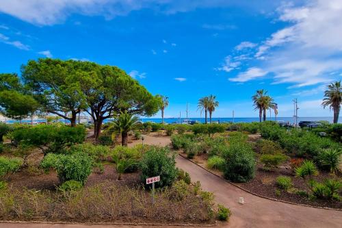 Apartment in Fréjus Plage by the seaside with direct access to the beach في فريجوس: حديقة فيها اشجار ونباتات وطريق