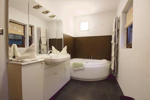 uma casa de banho com um lavatório, uma banheira e um espelho. em Finhäusl - Urlaub bei Oma em Aldino