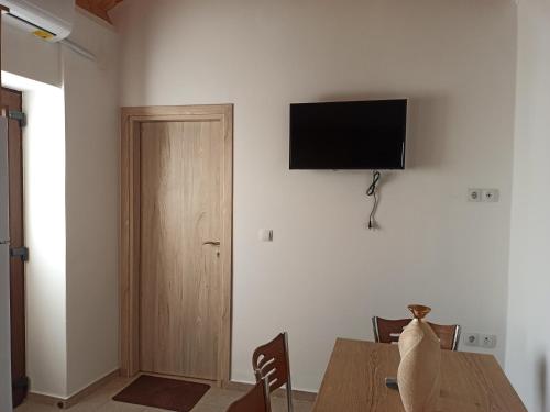 a dining room with a table and a television on a wall at Aloni Cottage above Aegean Sea in Raches