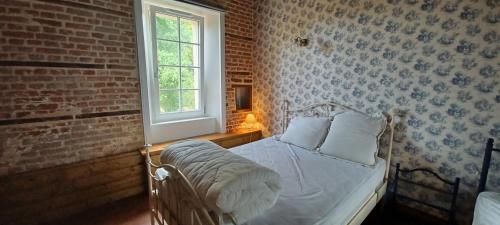 1 dormitorio con cama blanca y pared de ladrillo en chambre aux tomettes au Major, en Belle-et-Houllefort