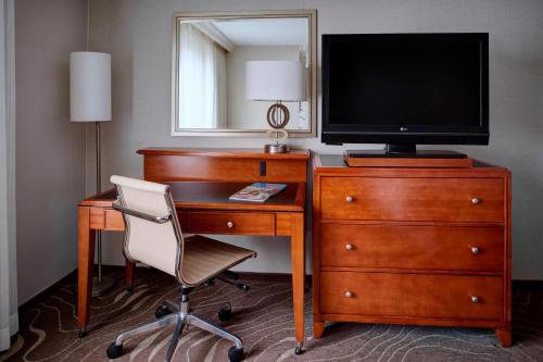 a hotel room with a desk with a television and a chair at Detroit Metro Airport Marriott in Romulus
