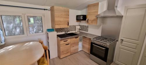 Il comprend une petite cuisine équipée d'une cuisinière et d'un évier. dans l'établissement Mobil Home O'HARA Confort Plus Parc Saint James Montana, à Gassin