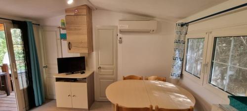 a dining room with a table and a television at Mobil Home O'HARA Confort Plus Parc Saint James Montana in Gassin