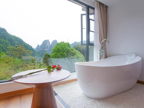 baño con bañera y ventana grande en Mount View Cottage, en Zhangjiajie