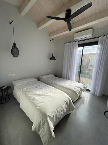 two beds in a bedroom with a ceiling fan at Casa Palma Pals 2 in Pals