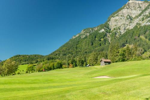 a green golf course with mountains in the background at Alpine Lodge Klösterle am Arlberg in Klösterle am Arlberg