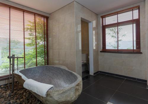 EBINO PULUONG RESORT في Pu Luong: حوض حجري كبير في حمام به نوافذ