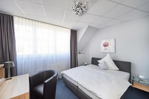 Habitación de hotel con cama, escritorio y lámpara de araña. en Komm' In Hotel, en Mechernich