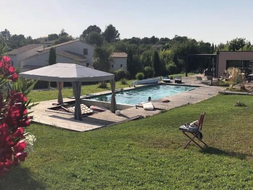 une personne assise dans une chaise à côté d'une piscine avec un parasol dans l'établissement Chalet bois cosy avec piscine Aix nature, à Aix-en-Provence