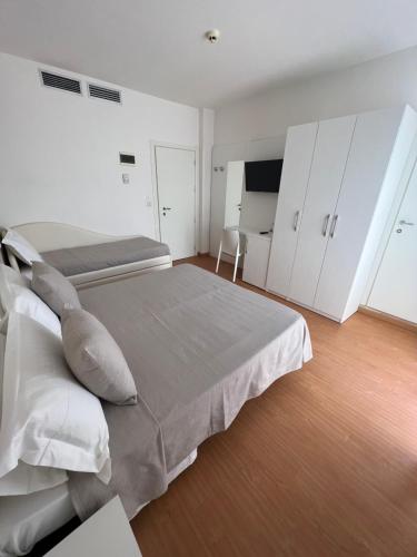 a white bedroom with two beds and a television at Hotel Ardea in Riccione