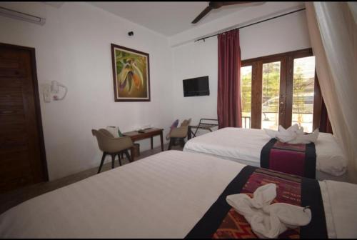 a hotel room with two beds and a table at Moonlight Champa Riverview in Luang Prabang