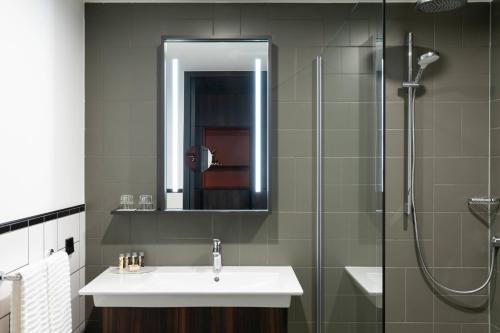 a bathroom with a sink and a shower with a mirror at Renaissance Amsterdam Schiphol Airport Hotel in Aalsmeer