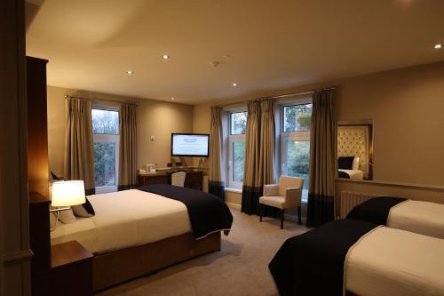 a hotel room with two beds and a desk at Glenavon House Hotel in Cookstown